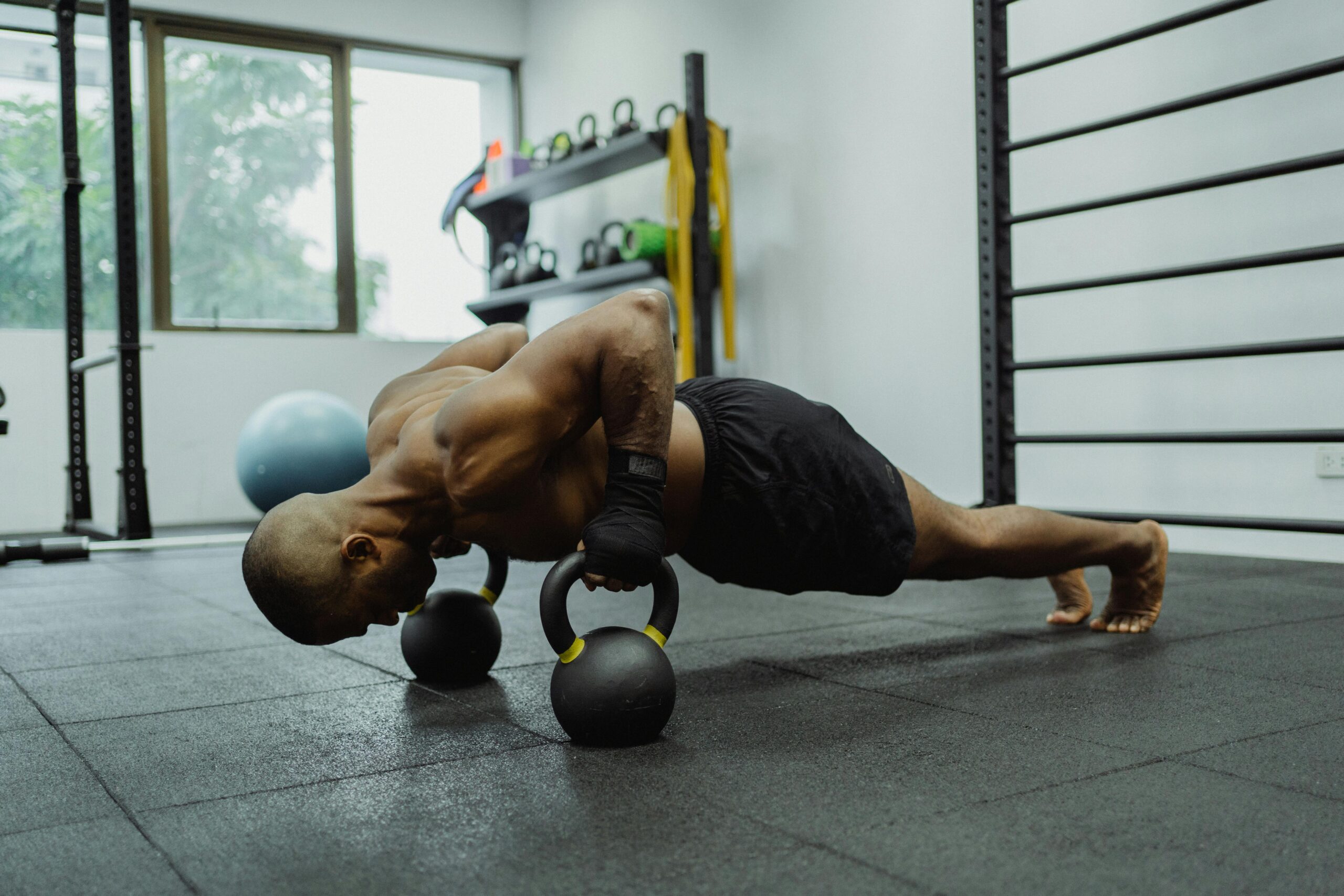 Man doing push ups in the gym using kettlebells.